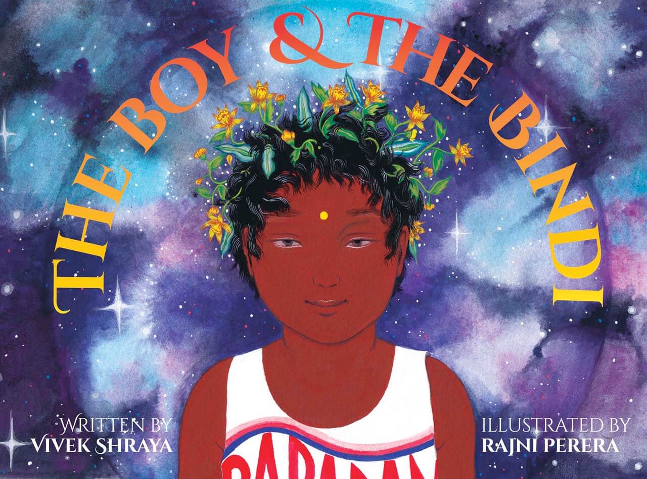 An illustration of a young, smiling, brown-skinned boy with flowers in his hair, against a colourful starry background. Text reads, The Boy & The Bindi; Written by Vivek Shraya; Illustrated by Rajni Perera.