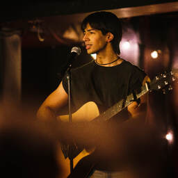 Vivek (Adrian Pavone) performs an acoustic set in 2002, in a still from How to Fail as a Popstar.